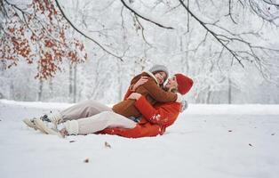 Lying down on the snow. Mother, and ,her daughter is on the winter meadow and forest photo