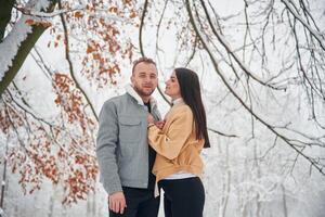 Beautiful couple are, standing together on the snowy field of forest photo