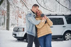 Beautiful ,couple standing near the car in the winter forest photo