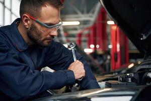 Hood ,is, opened, fixing. Car repairman is in the garage with automobile photo