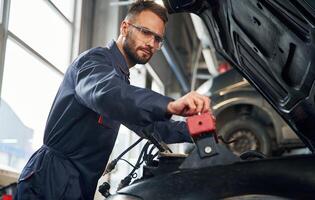 Car ,repairman,, is in the garage with automobile photo