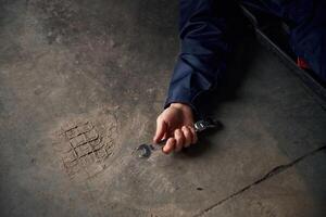 Repairman, is, lying down on the ground with tool in hand photo