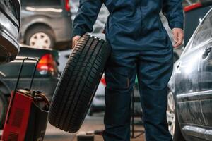 Holding, it in hand. Close up view of man that is moving tire of the car photo
