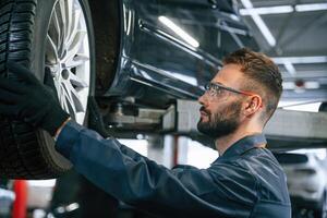 Fixing,, broken vehicle. Car repairman is in the garage with automobile photo
