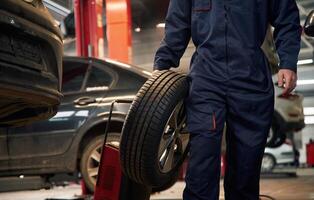 Holding,, it in hand. Close up view of man that is moving tire of the car photo