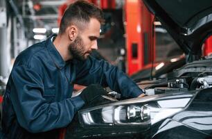 Busy car, repairman is in the garage with automobile, fixing it photo