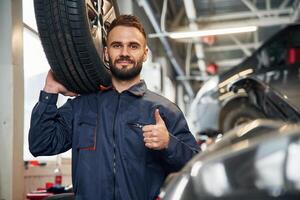 With ,brand new tire. Car repairman is in the garage with automobile photo