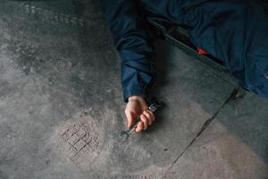 Repairman, is lying down on the ground with tool in hand photo