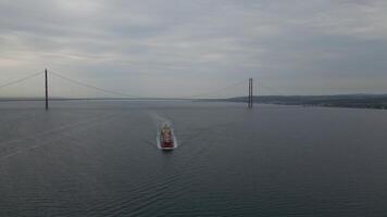 Aerial drone view of cargo ship passing under suspension bridge in Turkey video