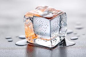 Melting ice cube with condensation on dark gray surface photo