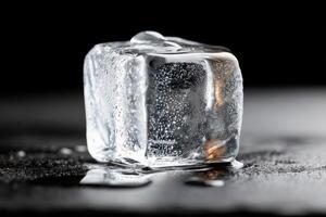 Ice cube melting on a dark surface with water droplets reflecting light creating a cool and refreshing atmosphere for summer drinks and beverages concept photo