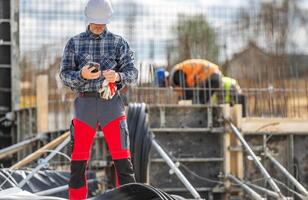 Construction Worker Checking Phone While Supervising Site Activity photo