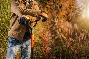 Gardener Leaning on Shovel in a Vibrant Autumn Garden Setting photo