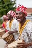 Group of african drummers wearing traditional clothes playing djembe drums and smiling photo