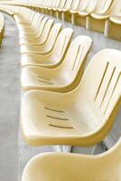 Rows of empty yellow plastic seats stretching into the distance in an old stadium photo