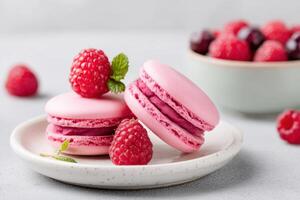 Pink raspberry macarons with fresh raspberries and mint leaves on a plate photo