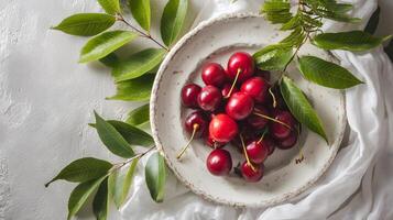 Fresh cherries beautifully arranged on a rustic white plate for an elegant yet charming display. photo