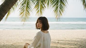 Bob hairstyle. Peaceful beach scene with woman in bob haircut relaxing under palm shadow, perfect for wellness and vacation ads. photo