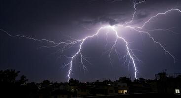 Dramatic lightning strikes illuminate the night sky over city rooftops during a thunderstorm photo