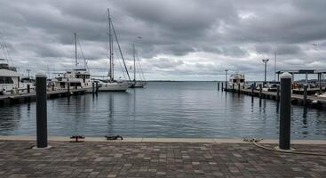 Cloudy marina view with boats docked at the pier on an overcast day, suggesting a calm atmosphere for leisure activities photo