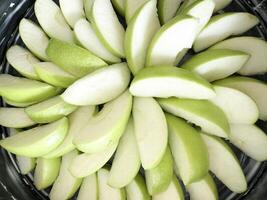 Green apple slices arranged in a circular pattern on a dark background photo