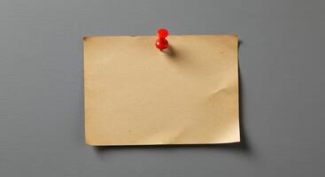Blank vintage brown paper note pinned to gray wall, suitable for advertisements, announcements, reminders, or as a background for quotes or text overlays. photo