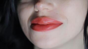 Macro shot of female lips with healed permanent makeup in warm red tones, showing precise lip contour and smooth texture under controlled beauty studio lighting video