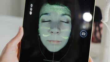 Close-up of facial skin scan on tablet during dermatological examination, woman's face analyzed under UV light for pores, texture and pigmentation mapping video