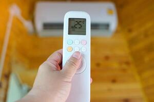 Mobile remote control adjusts the temperature of the air conditioner in the house to 25 degrees Celsius to save electricity. photo