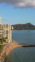 Aerial view Honolulu skyline with oceanfront resorts, Fort DeRussy Beach with golden sand, palm trees, and Diamond Head mountain in the background video