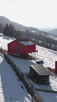 Red cabins on a snowy hillside, remote winter retreat with panoramic mountain views, wooden fences and untouched nature in a peaceful setting video