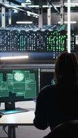 Vertical Server hub admin responds to cyberattack attempting to access confidential data while securing hardware systems. Data center worker fighting malware intrusion during security incident, camera A video