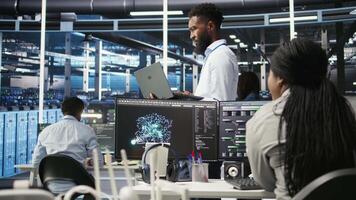 Data center system administrator analyzing infrastructure issues using node tree tools. Man in server hub using AI visualization insights on laptop to optimize system health, camera A video