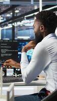 Vertical Data center programmer uses neural networks node tree program to identify equipment issues. Server hub employee reviewing AI deep learning data analysis graph to minimize failures, camera A video