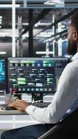 Data center programmer uses machine learning node tree program to identify equipment issues. Server hub worker reviewing artificial intelligence data analysis graph to minimize failures, camera A video