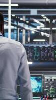 Vertical Server hub programmer using AI machine learning node tree software to optimize system health. Data center IT expert analyzing equipment issues using artificial intelligence visualization, camera A video