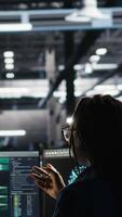 Vertical Server hub manager talking with programmer using node tree software to optimize system health. Data center supervisor overseeing IT expert analyzing equipment issues using AI visualization, camera B video