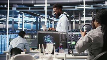 Happy data center admin uses node tree programming on laptop to identify equipment performance issues. Cheerful server farm worker reviews data analysis graph to minimize hardware failures, camera A video