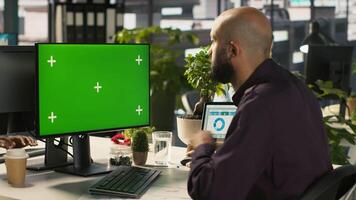 Employee at work using isolated screen PC to check progress done on customer commissioned project. Office clerk in front of mockup computer reading data statistics on paperwork after audit, camera A video
