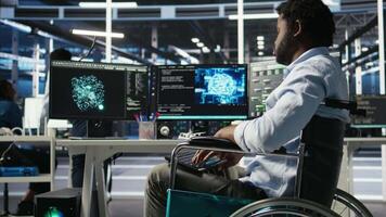 Engineer using wheelchair in data center using AI node tree software to minimize system downtime. Server hub worker in disability using visual programming to monitor performance, camera A video