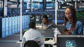 Portrait of smiling server room engineer using device to interpret data analytics graphs. Happy data center worker using artificial intelligence tool showing system metrics, camera A video
