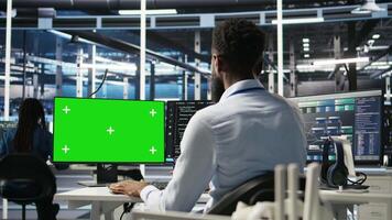 Vertical Data center admin using green screen PC to do node tree programming, optimizing resource allocation. Man in server room uses mockup computer predictive AI visualization systems, camera A video