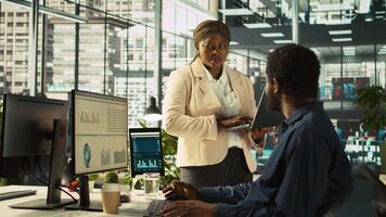Worker in office receiving feedback from management executive looking over work done on laptop. African american manager in workspace giving tasks to employee, providing necessary data, camera B video