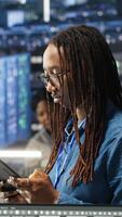 Woman in server hub using AI visualization insights on tablet device to optimize system health. Data center computer scientist analyzing infrastructure issues using node tree tools, camera B video