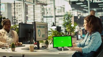 Close up of employee sitting at office desk, using green screen tablet to solve tasks during job shift. Office clerk doing email communication in workplace using chroma key device, camera B video