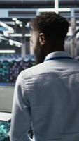 Vertical Server hub engineering team interprets data analytics graphs. Teamworking data center colleagues using artificial intelligence program showing predictive system metrics, camera A video