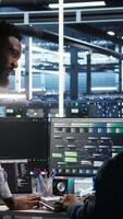 Vertical Data center manager supervising engineer using node tree tool to identify equipment performance issues. Server hub team leader talks with IT specialist reviewing data analysis graph, camera A video