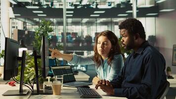 Team leader showing employee mistakes to fix in business documents on PC. African american man and manager analyzing company information records in office using computer, camera B video
