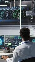 Data center admin using artificial intelligence neural network models to configure hardware. Man works on AI programming language in server room, optimizing system functionality, camera A video