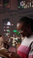 Vertical African american girl reading and taking notes for exam at the college, studying political science for upcoming class lesson in a library at university. Young student consults textbooks. Camera B. video